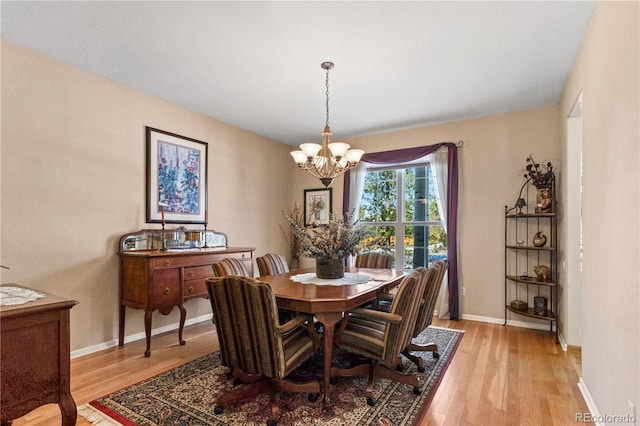 dining room with light hardwood / wood-style flooring and an inviting chandelier