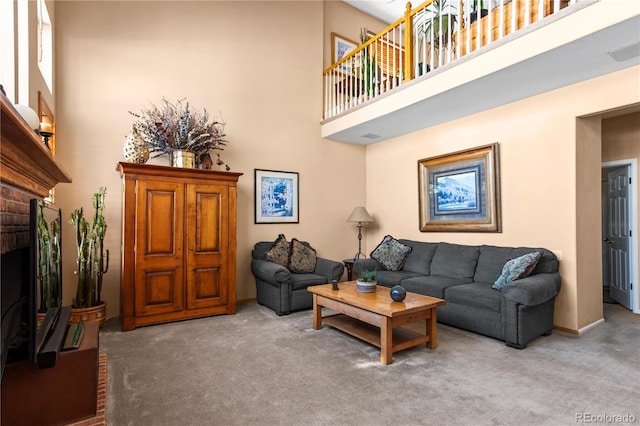 carpeted living room with a towering ceiling and a brick fireplace