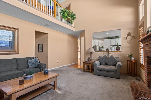 carpeted living room with a fireplace and a high ceiling