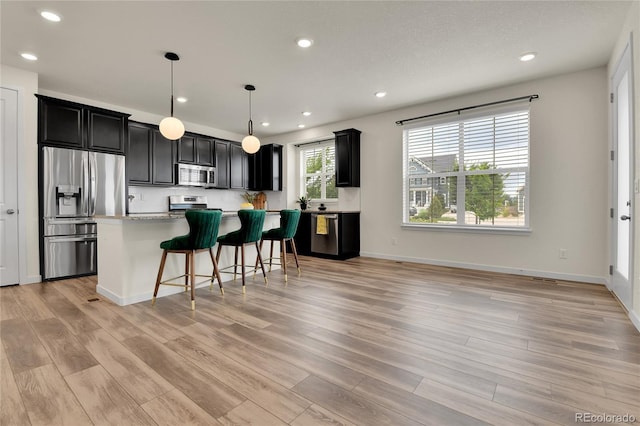 9307 Inca Dove Cir, Littleton, CO 80125 - kitchen featuring stainless steel appliances, dark cabinets, light wood finished floors, light countertops, and a kitchen bar