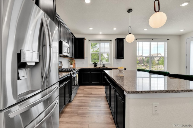 9307 Inca Dove Cir, Littleton, CO 80125 - kitchen featuring stainless steel appliances, dark cabinetry, light wood-style flooring, a kitchen island, and recessed lighting