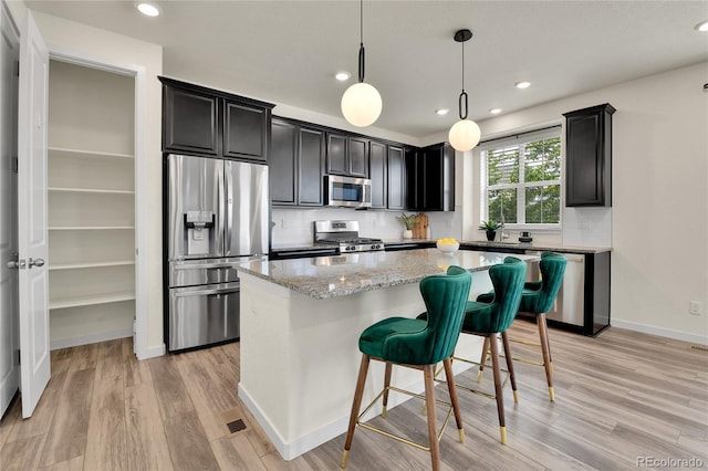 9307 Inca Dove Cir, Littleton, CO 80125 - kitchen featuring stainless steel appliances, dark cabinets, light wood-type flooring, a kitchen island, and recessed lighting