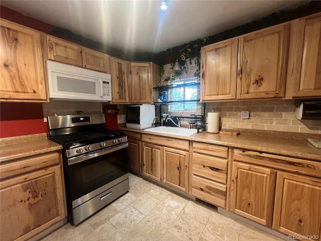 187 Johnson Rd, Bailey, CO 80421 - kitchen with white microwave, stainless steel range with gas stovetop, tasteful backsplash, and light stone finish floors