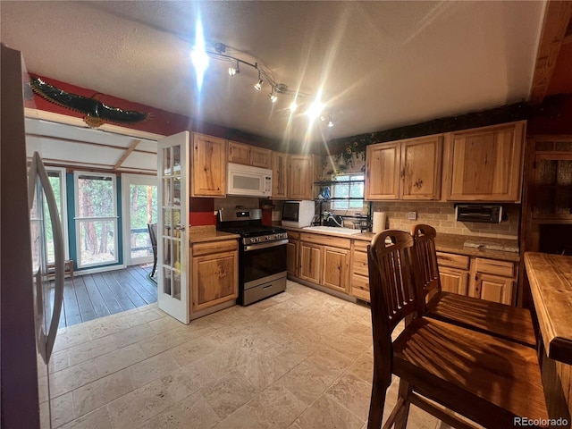 187 Johnson Rd, Bailey, CO 80421 - kitchen with stainless steel gas stove, white microwave, light countertops, backsplash, and a textured ceiling