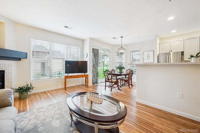 8520 S Holland Ln Unit 102, Littleton, CO 80128 - living room featuring baseboards, light wood-type flooring, a tiled fireplace, recessed lighting, and a chandelier