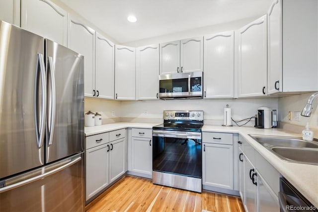 8520 S Holland Ln Unit 102, Littleton, CO 80128 - kitchen with stainless steel appliances, a sink, light wood-style flooring, light countertops, and recessed lighting
