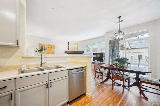8520 S Holland Ln Unit 102, Littleton, CO 80128 - kitchen featuring dishwasher, a sink, light wood finished floors, hanging light fixtures, and a peninsula