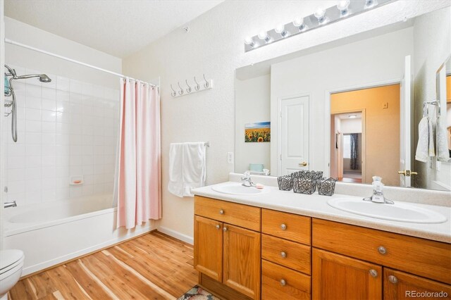 8520 S Holland Ln Unit 102, Littleton, CO 80128 - bathroom with double vanity, wood finished floors, toilet, and shower / bathtub combination with curtain