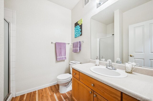 8520 S Holland Ln Unit 102, Littleton, CO 80128 - full bathroom with wood finished floors, a stall shower, baseboards, toilet, and vanity
