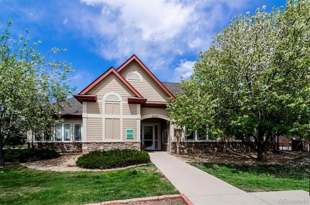 8520 S Holland Ln Unit 102, Littleton, CO 80128 - craftsman inspired home featuring a front lawn, stone siding, and roof with shingles