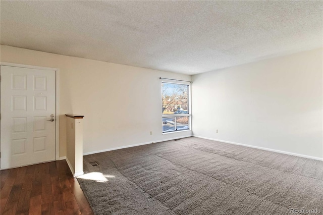 unfurnished room featuring dark wood-type flooring and a textured ceiling