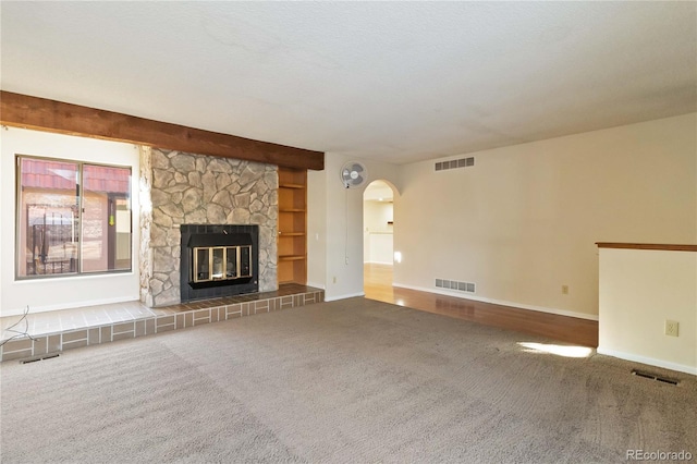 unfurnished living room featuring a stone fireplace, carpet floors, and a textured ceiling