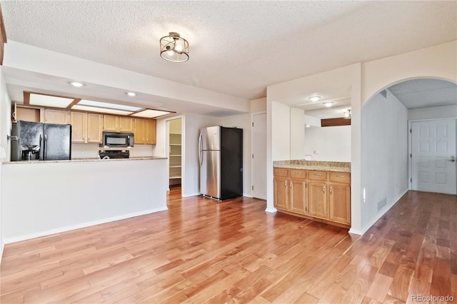 kitchen with kitchen peninsula, a textured ceiling, light hardwood / wood-style floors, and black appliances