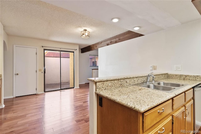 kitchen featuring light stone counters, a textured ceiling, sink, beam ceiling, and light hardwood / wood-style flooring