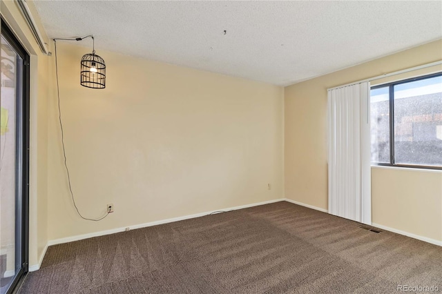 carpeted empty room with a textured ceiling