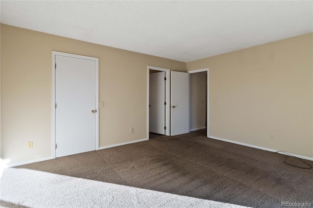 unfurnished bedroom with dark colored carpet and a textured ceiling