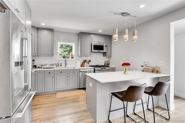 3178 N Race St, Denver, CO 80205 - kitchen with gray cabinets, appliances with stainless steel finishes, a sink, a breakfast bar, and a peninsula