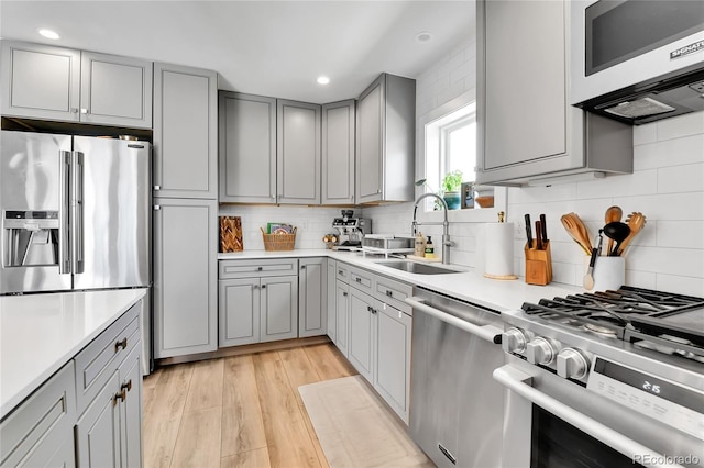 3178 N Race St, Denver, CO 80205 - kitchen with stainless steel appliances, gray cabinetry, a sink, tasteful backsplash, and light countertops