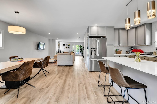 3178 N Race St, Denver, CO 80205 - kitchen featuring stainless steel fridge, gray cabinetry, light countertops, a breakfast bar, and light wood-type flooring