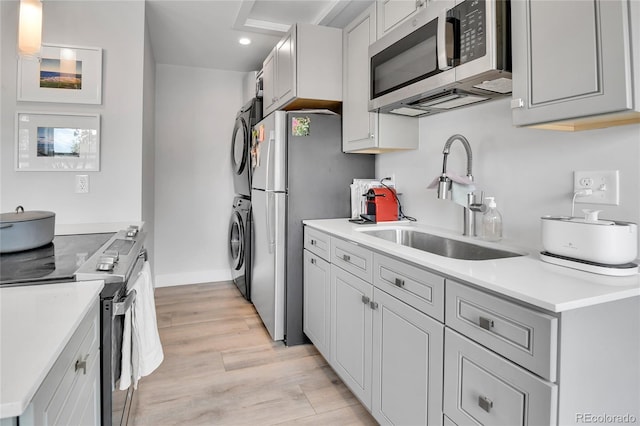 3178 N Race St, Denver, CO 80205 - kitchen featuring appliances with stainless steel finishes, a sink, stacked washing machine and dryer, recessed lighting, and light countertops
