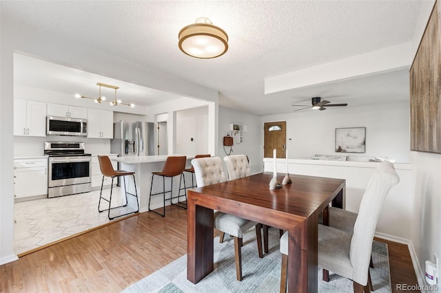 8369 W 77th Way, Arvada, CO 80005 - dining room with ceiling fan, light wood-style flooring, and a textured ceiling