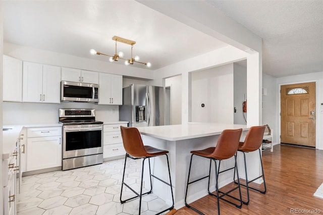 8369 W 77th Way, Arvada, CO 80005 - kitchen featuring appliances with stainless steel finishes, a kitchen breakfast bar, light countertops, and white cabinets