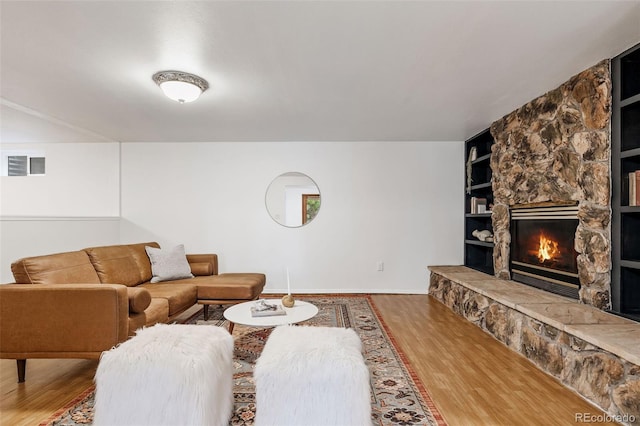 8369 W 77th Way, Arvada, CO 80005 - living room with wood finished floors, built in features, and a stone fireplace