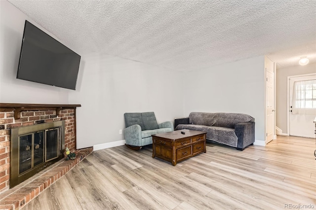 10685 W Apishapa Pass, Littleton, CO 80127 - living room with light wood-style flooring, a textured ceiling, baseboards, and a brick fireplace
