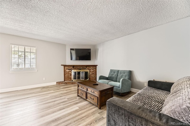 10685 W Apishapa Pass, Littleton, CO 80127 - living room featuring light wood-style floors, a textured ceiling, a brick fireplace, and baseboards