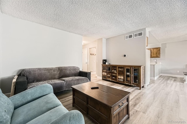 10685 W Apishapa Pass, Littleton, CO 80127 - living room with light wood-type flooring, a textured ceiling, and baseboards