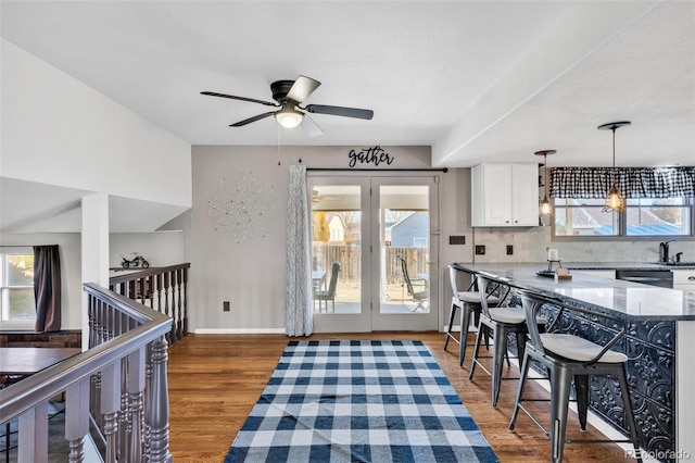 kitchen with ceiling fan, tasteful backsplash, decorative light fixtures, dark hardwood / wood-style flooring, and white cabinetry