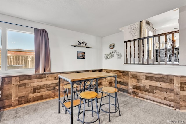 dining room featuring light carpet and wooden walls