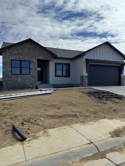 view of front of home featuring stone siding, an attached garage, driveway, and board and batten siding