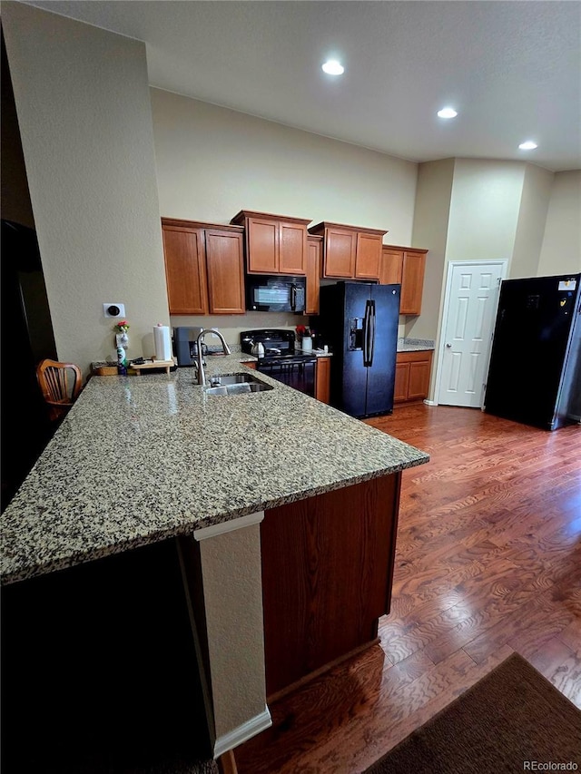 5131 Delphinium Cir, Brighton, CO 80601 - kitchen featuring black appliances, a sink, a peninsula, light stone counters, and dark wood-type flooring