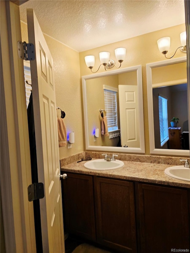 5131 Delphinium Cir, Brighton, CO 80601 - bathroom featuring double vanity, a textured ceiling, and a textured wall