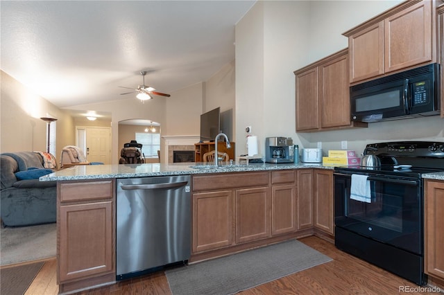 5131 Delphinium Cir, Brighton, CO 80601 - kitchen featuring black appliances, open floor plan, a peninsula, dark wood-style floors, and arched walkways