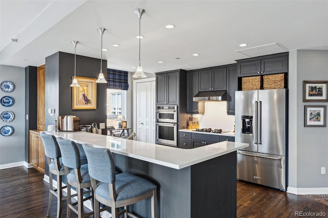 kitchen with pendant lighting, a breakfast bar, appliances with stainless steel finishes, dark hardwood / wood-style flooring, and kitchen peninsula