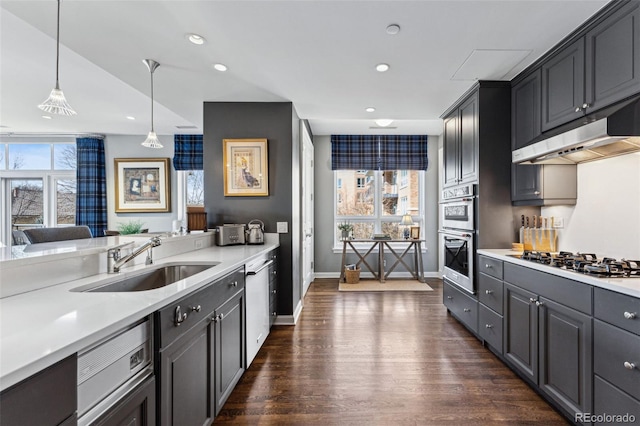 kitchen featuring appliances with stainless steel finishes, sink, dark wood-type flooring, and decorative light fixtures