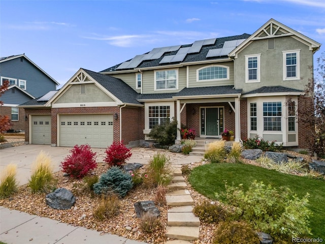 view of front of home featuring solar panels, brick siding, an attached garage, and driveway