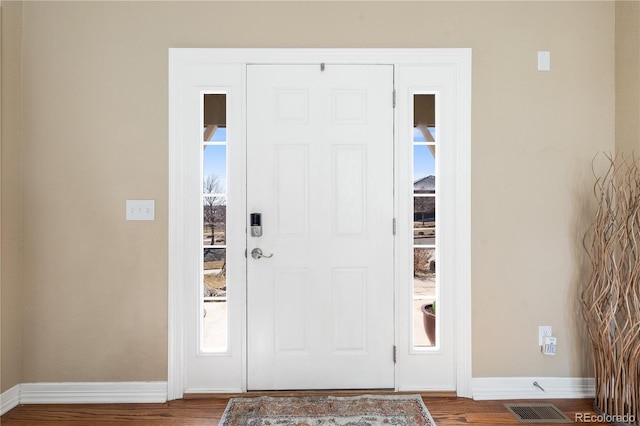 foyer with wood finished floors, visible vents, and baseboards