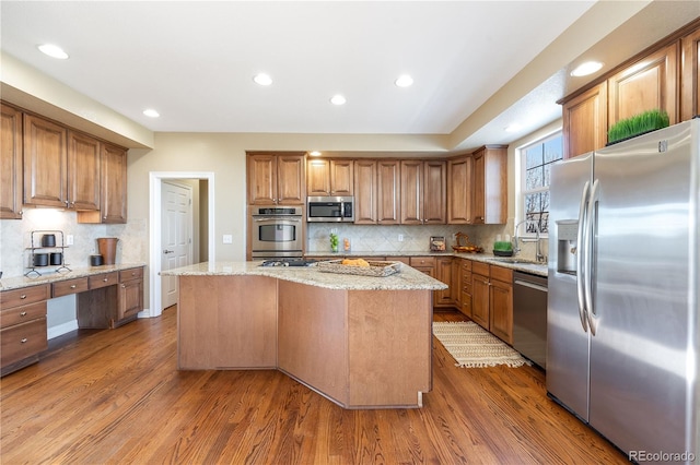 kitchen featuring brown cabinets, stainless steel appliances, wood finished floors, and a center island