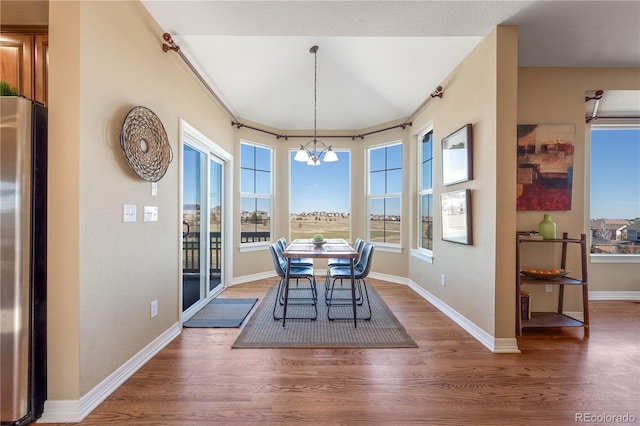 dining room with baseboards, wood finished floors, and an inviting chandelier