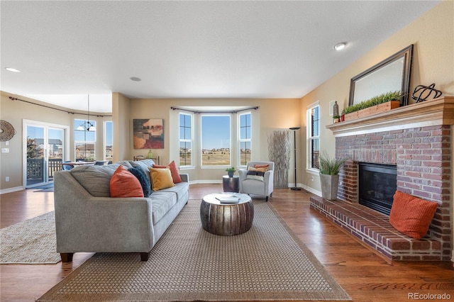 living area with a fireplace, baseboards, and wood finished floors