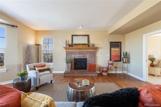 living room featuring a fireplace, baseboards, and wood finished floors