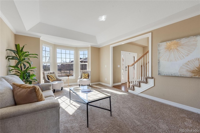 carpeted living area featuring ornamental molding, a tray ceiling, baseboards, and stairs