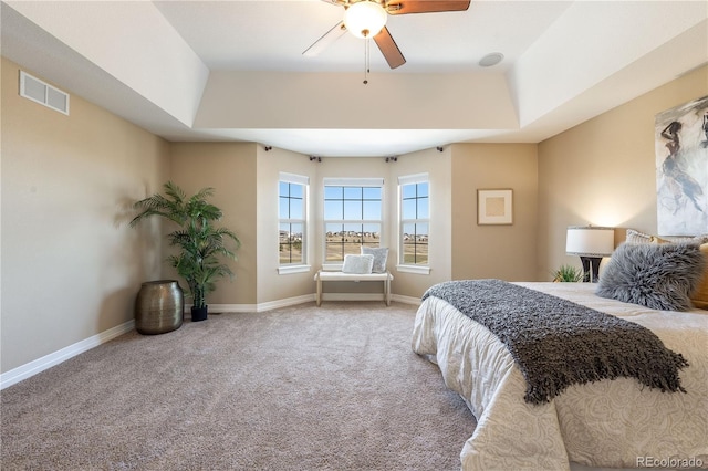 carpeted bedroom with a raised ceiling, visible vents, and baseboards