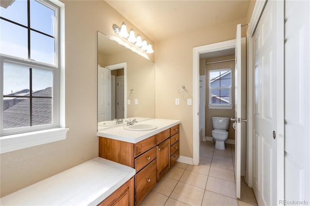 bathroom with toilet, baseboards, vanity, and tile patterned floors