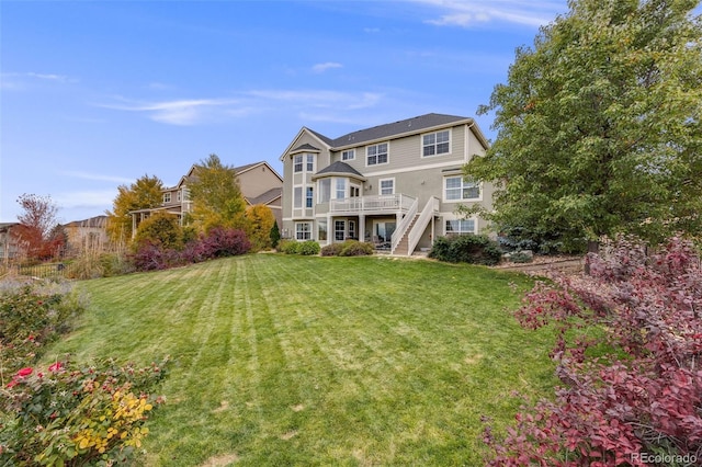 rear view of property featuring a lawn and stairway