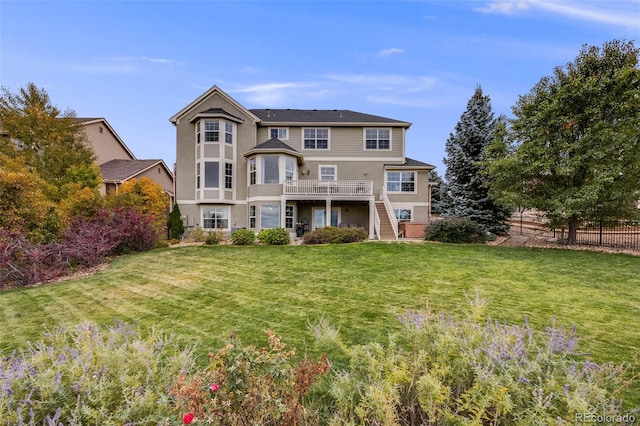 back of property with fence, stairway, a deck, and a lawn