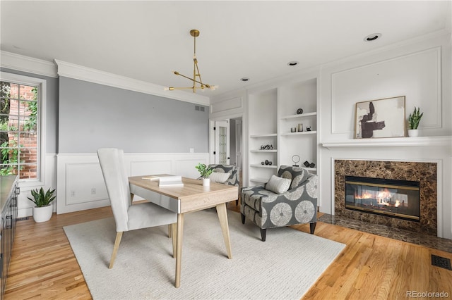 18963 E Long Ave, Centennial, CO 80016 - dining room featuring crown molding, a chandelier, light wood finished floors, built in features, and a wainscoted wall